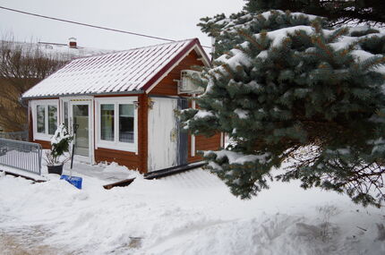 Tiny house im Winter mit Schnee und Baum