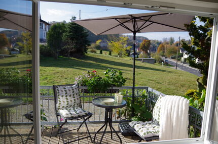 Blick aus dem Fenster auf die Gartenstühle, den Sonnenschirm, den Garten und die herrliche Natur