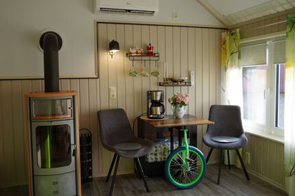 Gemütliche Sitzecke mit Kaffeemaschine , Tisch, 2  bequemen Sesseln, Kamin und Klimaanlage. Der Tisch hat ein Fahrrad als Bein